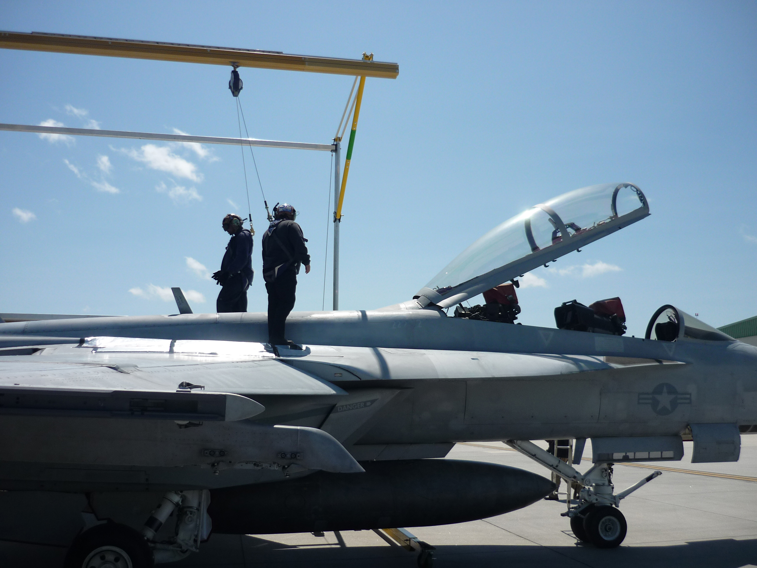 Aircraft maintenance crew working on top of a military jet, protected by an engineered fall protection system from Evan Fall Protection. The height safety system ensures worker safety during elevated maintenance tasks in the aviation field.